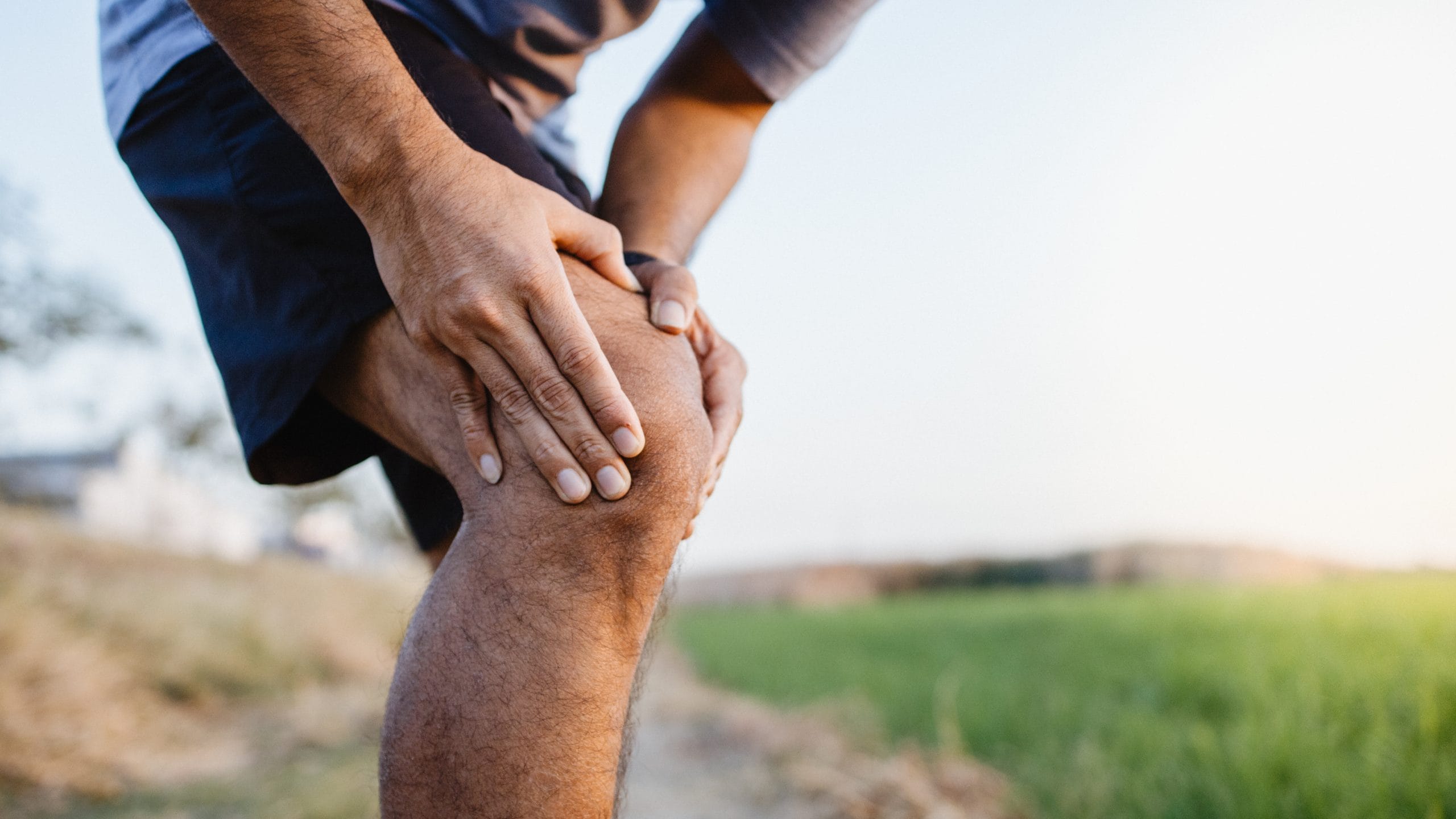 Sporty man in pain after sustaining a knee injury during a running