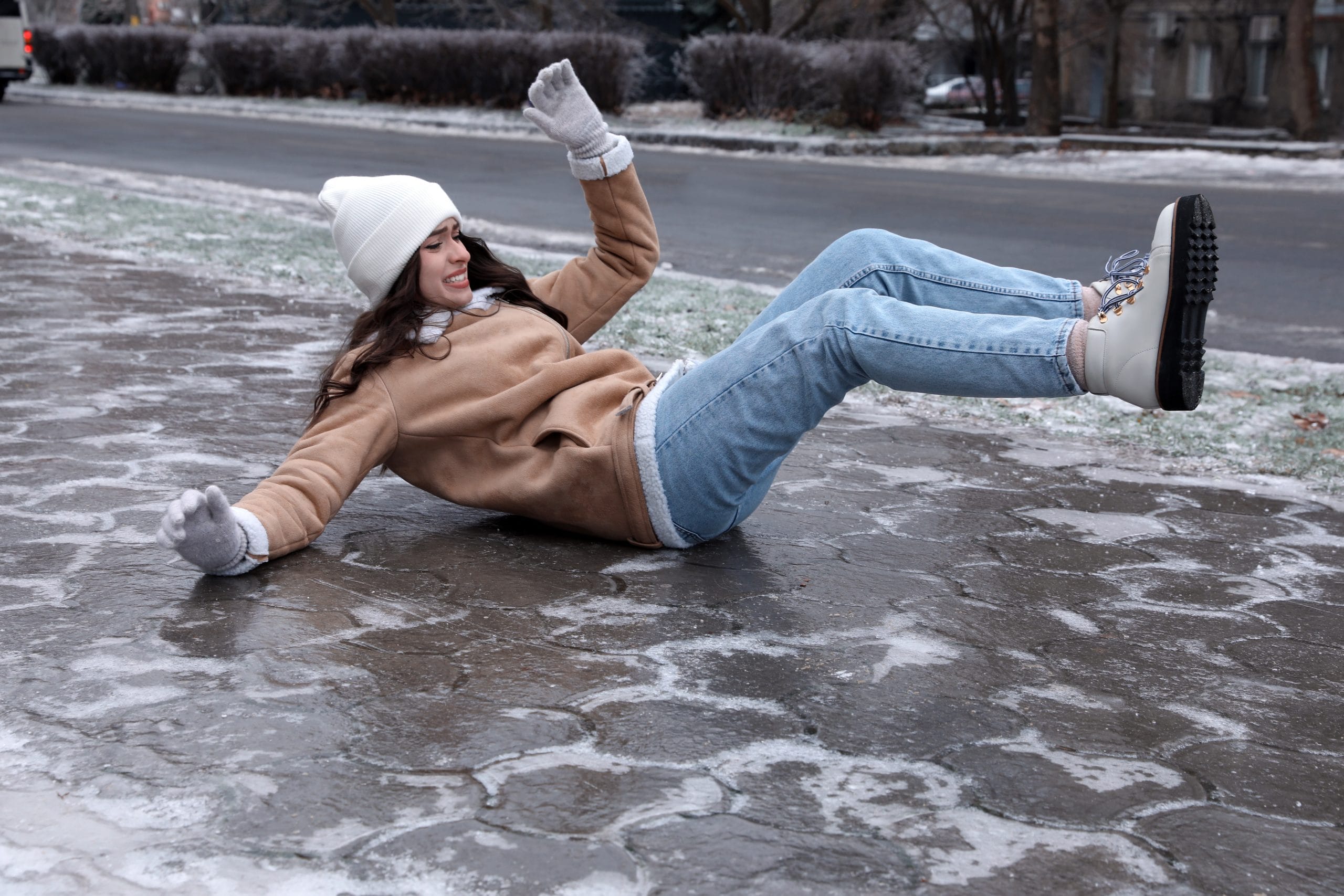 Young woman fallen on slippery icy pavement outdoors